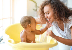 Young,African-american,Mother,Washing,Her,Baby,At,Home